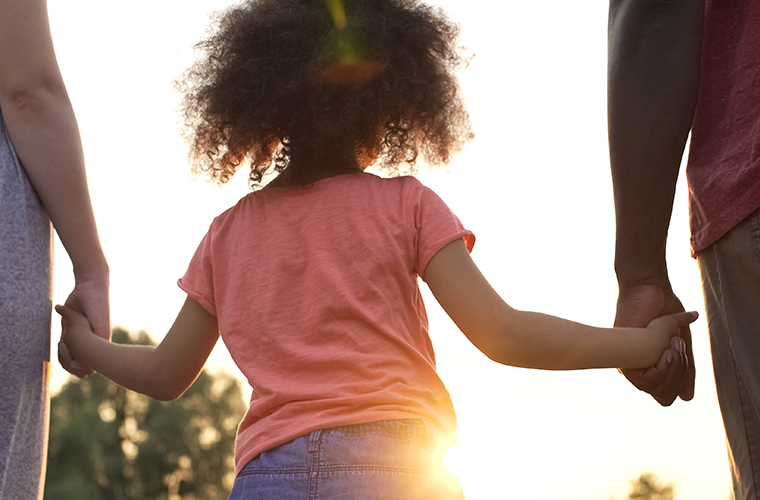Little girl holds fathers and mothers hands